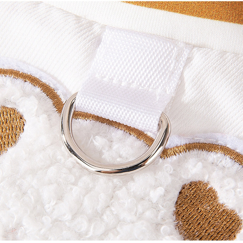 Close-up of tan/gold-trim pet jacket with metal leash ring and embroidered fabric