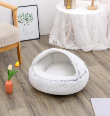 Round plush pet bed in white with soft cushioned sides and oval cave opening