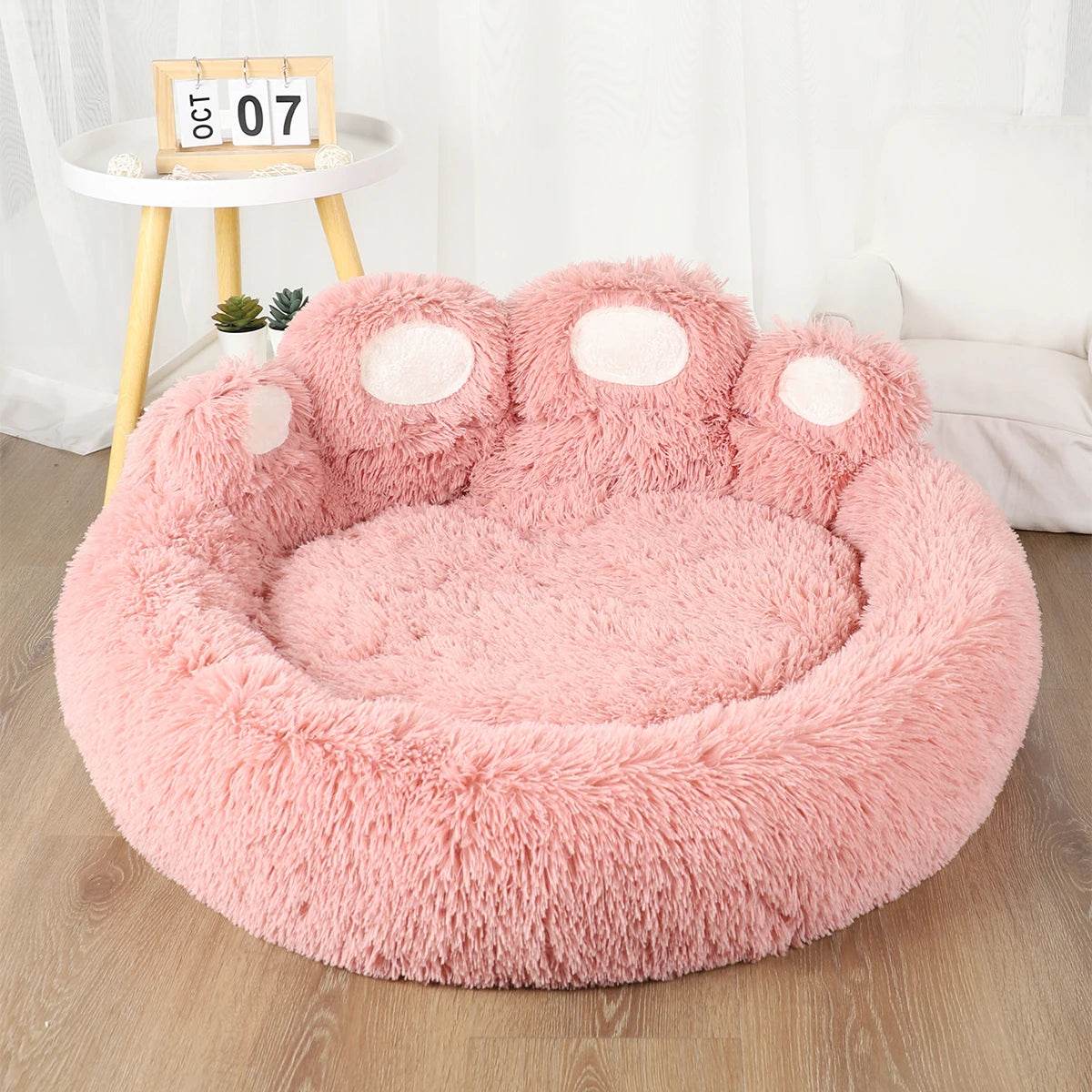 Pink plush pet sofa bed with paw-shaped bolsters and fluffy round sleeping area