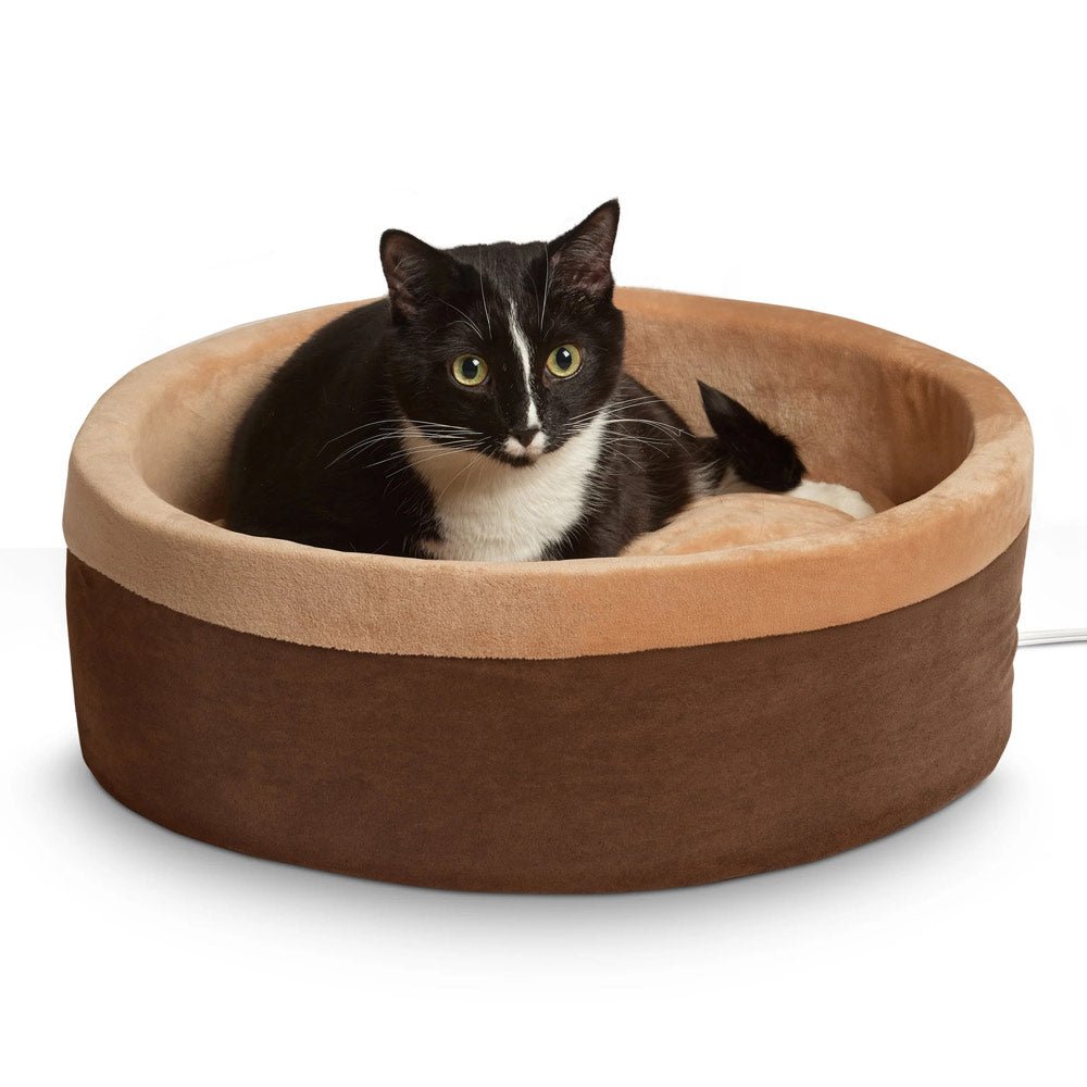 Heated cat bed with dark brown outer fabric and beige top cushion, with black-and-white cat
