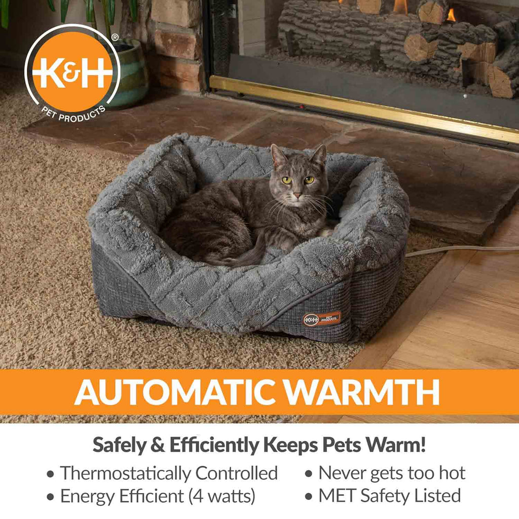 Grey plush heated pet bed with curled bolsters; grey cat sleeping inside