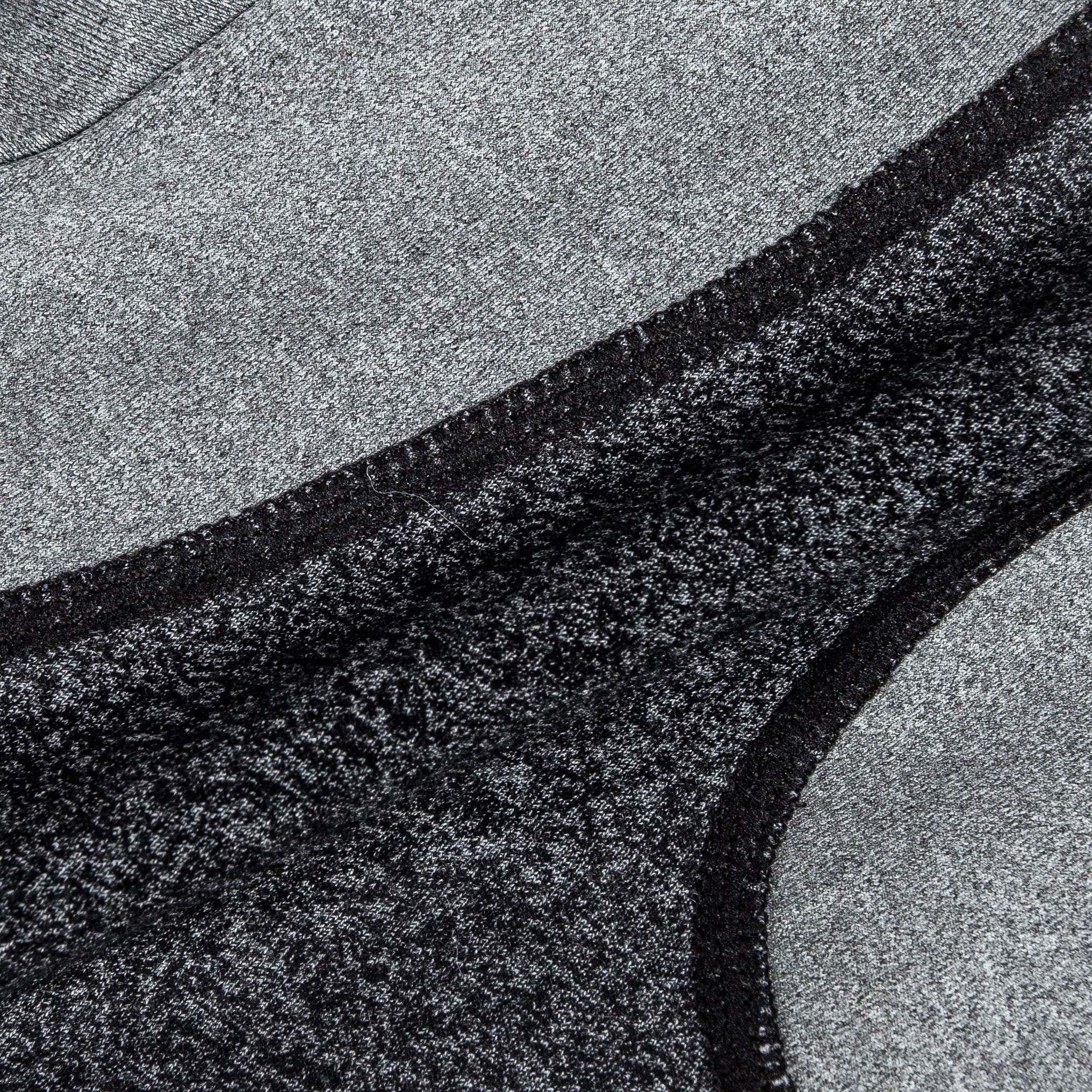 Close-up of dark heather knit with light gray panel and black edge stitching