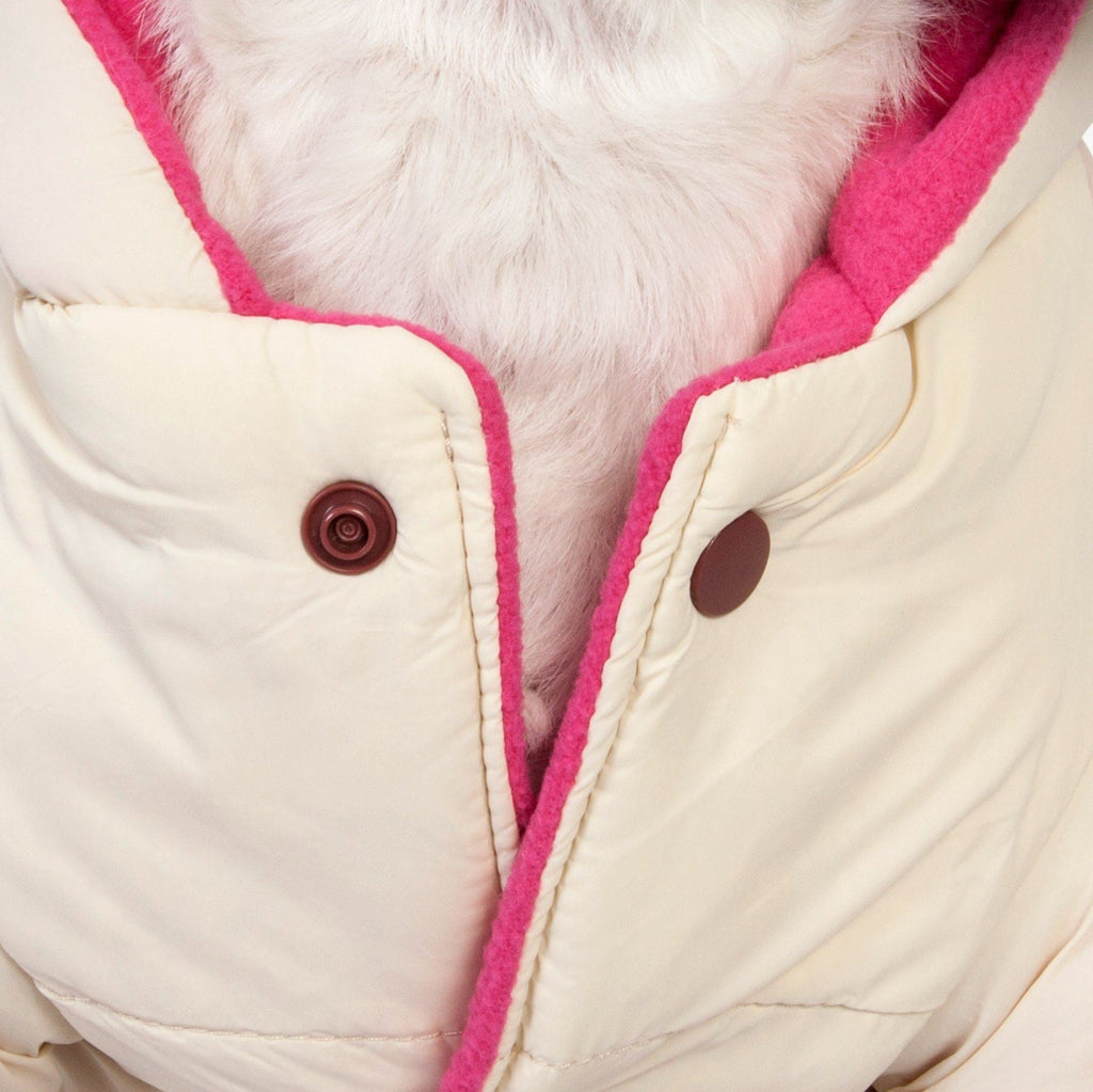 Close-up of cream dog jacket with pink trim and snap buttons on front placket
