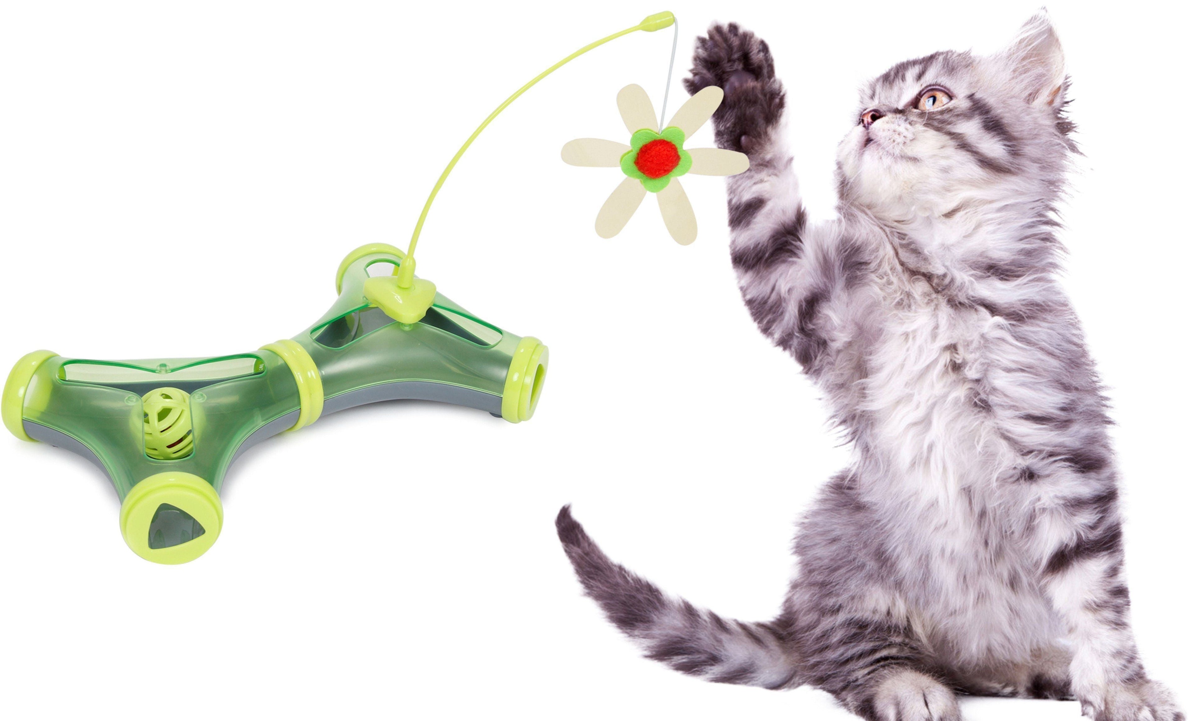 Green interactive teaser cat puzzle toy with flower charm and feathers; gray tabby cat playing