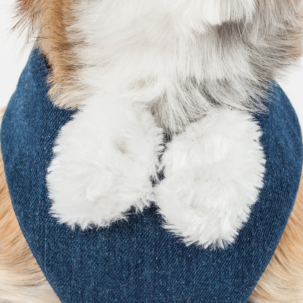 Close-up of white faux-fur pom trim on denim-blue harness bib