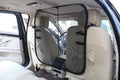 Gray mesh backseat safety barrier with hook straps, attached between car seats