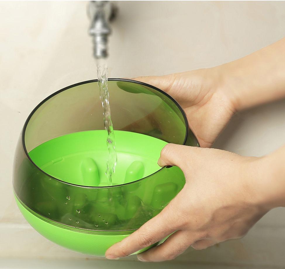 Slow feeding pet bowl, green base with clear dome while water pours into the bowl