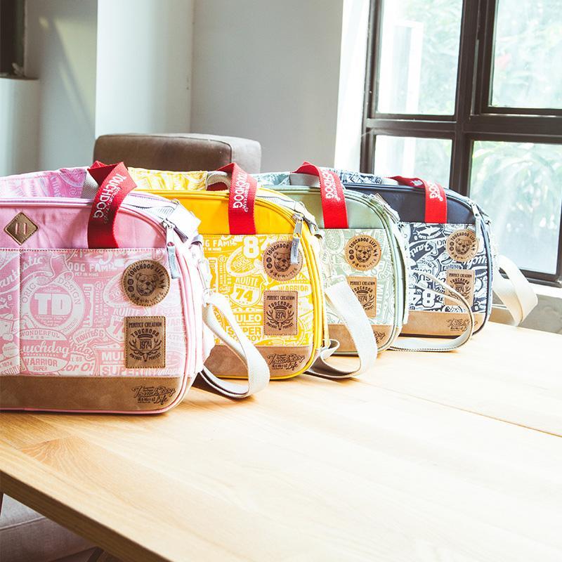 Assorted pet carrier duffels in pink, yellow, and light blue with red straps
