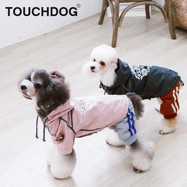 Two small dogs wearing hooded reversible raincoats: one pink, one dark charcoal-gray