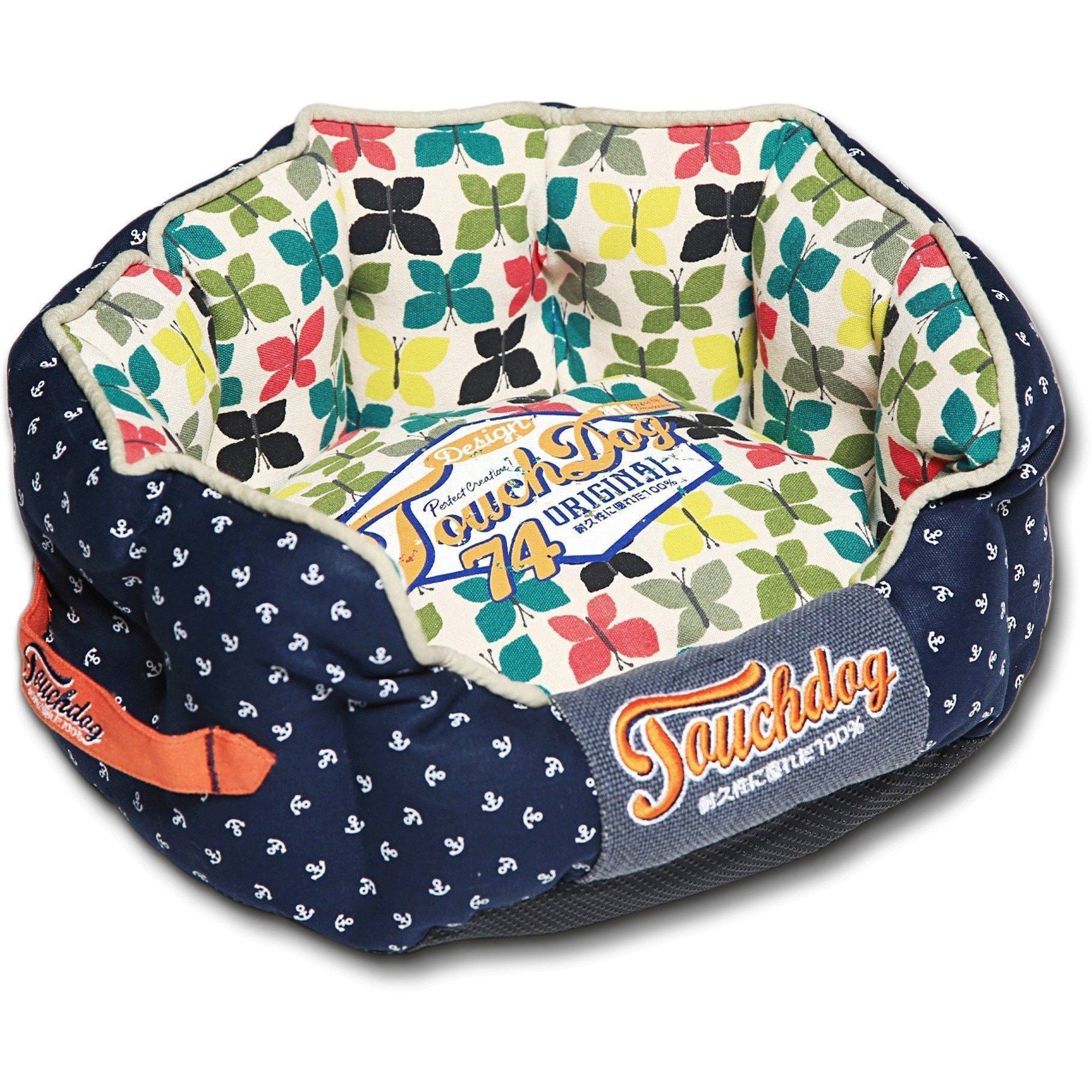 Rounded dog bed with navy outer fabric, floral butterfly print interior, padded bolster