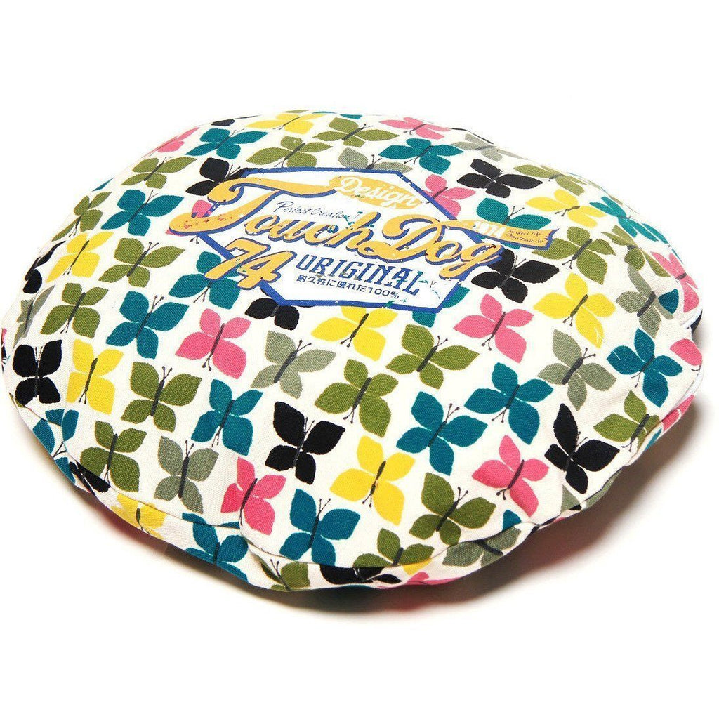 Rounded dog bed top with colorful butterfly pattern on a light fabric cover